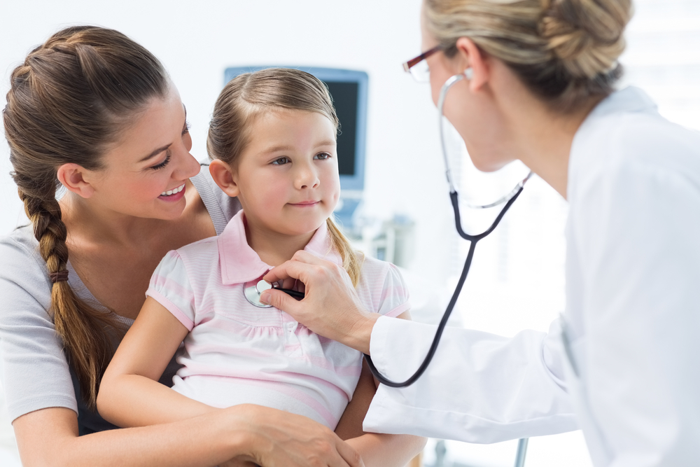 Madre con niña siendo examinada por una pediatra en una clínica