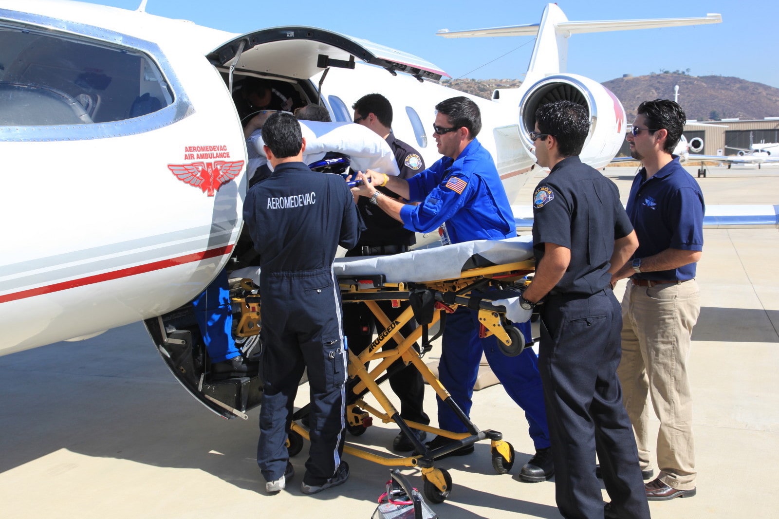 El equipo aéreo y terrestre de Aeromedevac se une para garantizar que un paciente sube correctamente a bordo de un avión de aeromedevac.